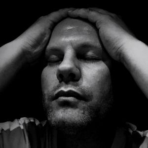 Close-up of man with headache against black background