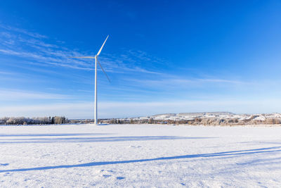 Wintry landscape view with a wind turbine at a snowy field