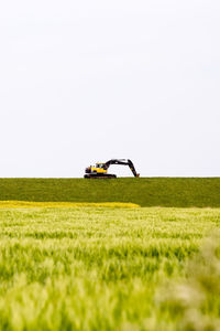 Tractor on grassy field against clear sky