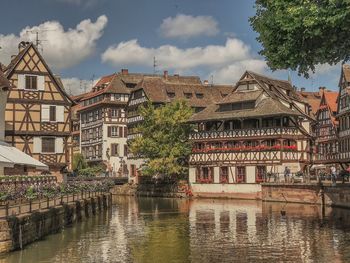 Houses by river in town against sky