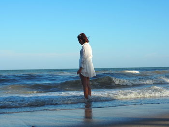 Full length of man standing on beach against clear sky