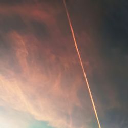 Low angle view of vapor trail in sky during sunset
