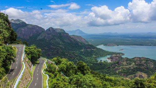 High angle view of mountain road by lake against cloudy sky