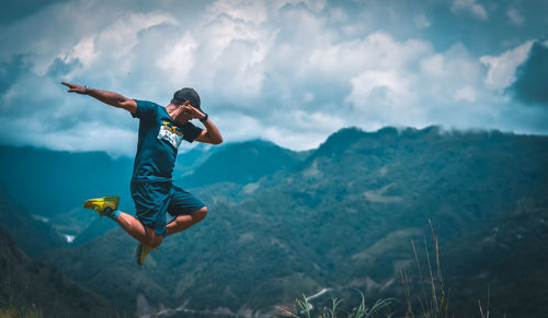 Man jumping in mountain against sky