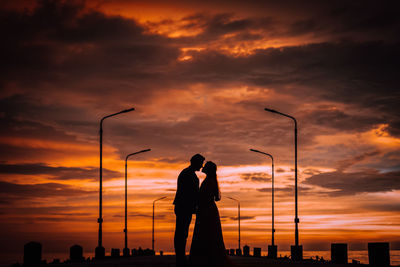Silhouette man standing on field against sky during sunset