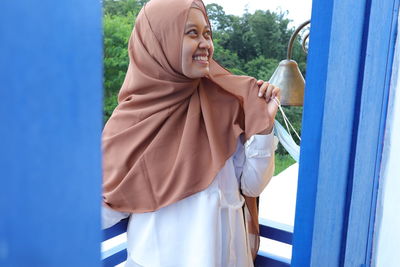 Girl in cream hijab and white dress on top of the white building