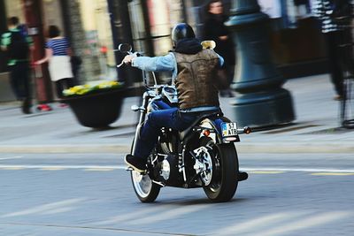 Blurred motion of people riding motorcycle on road