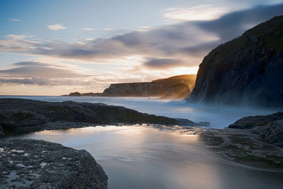Scenic view of waterfall against sky during sunset