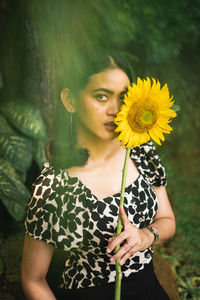 Portrait of woman holding sunflower standing outdoors