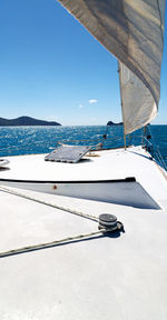 Sailboat sailing in sea against clear blue sky