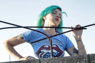 Low angle view of young woman standing against sky