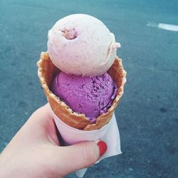 Cropped hand holding ice cream cone on street