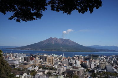 High angle view of city by sea against blue sky