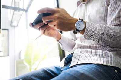 Midsection of man using mobile phone