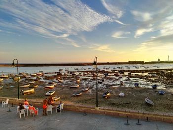 People at beach against sky during sunset