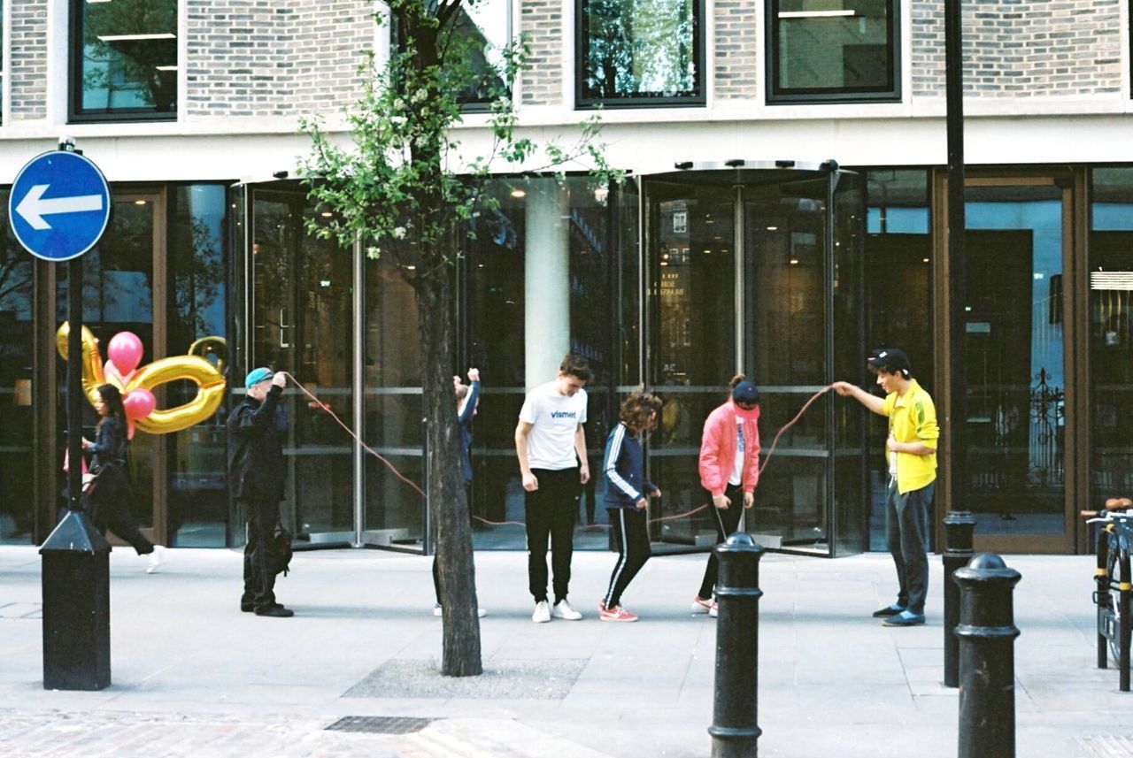 PEOPLE STANDING ON STREET AGAINST BUILDINGS