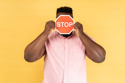 Rear view of man wearing hat against yellow background
