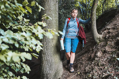 Active woman walking on forest path, actively spending summer vacation, carrying backpack