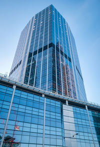 Low angle view of modern glass building against blue sky