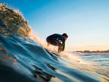 Mature man surfing in sea against sky during sunset