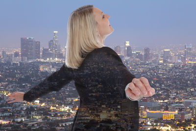 Woman standing by modern buildings against sky in city