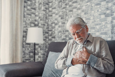 Senior man sitting on sofa at home