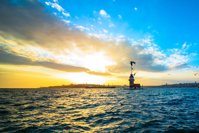 Silhouette sculpture by sea against sky during sunset