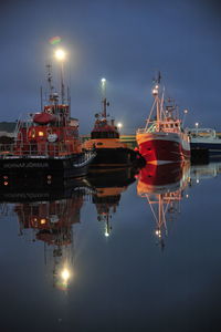 Illuminated ship moored at harbor against sky at night