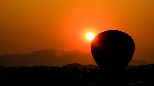 Silhouette hot air balloon against sky during sunset