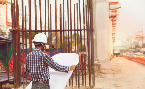 Rear view of man standing at construction site in city