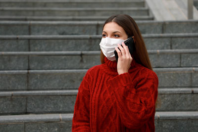 Young woman wearing mask talking on mobile phone outdoors