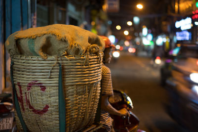 Close-up of man carrying wicker basket on scooter in city