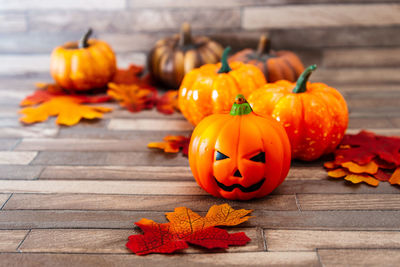 Jack o lantern and artificial pumpkins on table