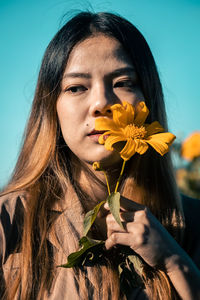 Portrait of beautiful woman holding red flowering plant