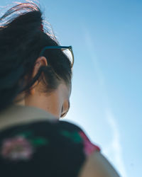 Side view of young woman against sky