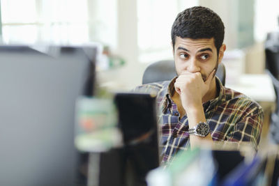 Businessman looking away while sitting at desk in creative office