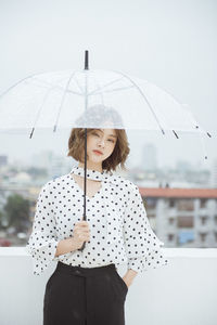 Young woman with umbrella standing on terrace