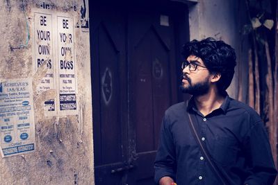 Young man standing by wall