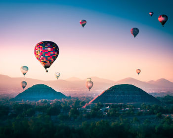 Hot air balloons flying over landscape against sky