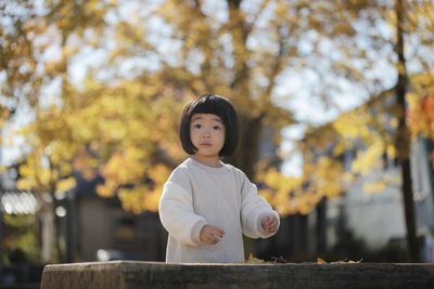 Portrait of cute girl standing against trees during autumn