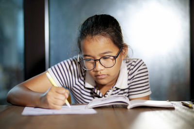 Close-up of boy with open book on table