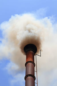 Low angle view of smoke emitting from chimney against sky