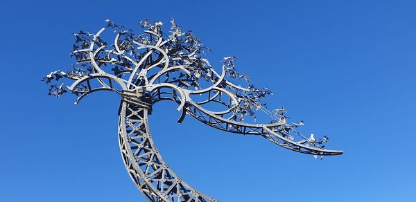 Low angle view of rollercoaster against clear blue sky