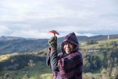 Rear view of woman with arms outstretched standing against mountain