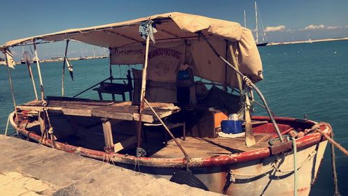 Fishing boat moored at beach against sky