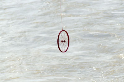 Bicycle hanging on rope against sea
