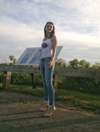 Full length portrait of young woman standing against tree