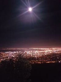 Illuminated city against sky at sunset