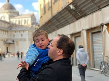 Father carrying crying son on footpath in city