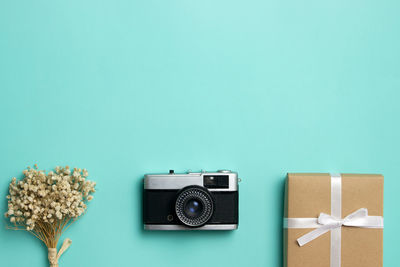 Gift box, camera and flowers over the green background.